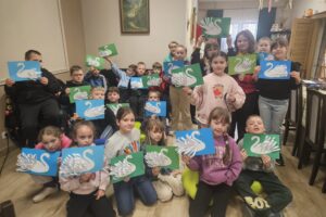 Grupa dzieci prezentująca swoje prace plastyczne - łabędzie.