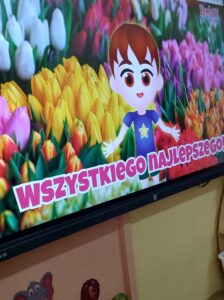 Tablica multimedialna, na której jest chłopiec a w tle tulipany.