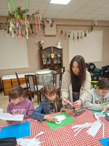Dzieci i instruktorka podczas warsztatów plastycznych.