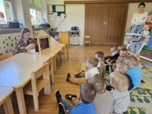 Grupa dzieci siedząca na podłodze oglądająca teatrzyk Kamishibai.