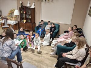 Dzieci słuchające książki czytanej przez kobietę.