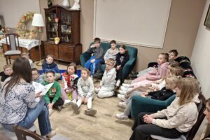 Dzieci słuchające książki czytanej przez kobietę.