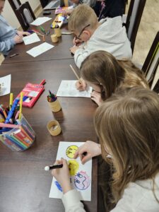 Grupa dzieci rysujących kredkami.