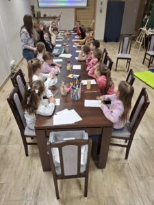 Grupa dzieci rysujących kredkami.