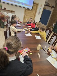 Grupa dzieci rysujących kredkami.