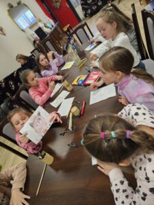 Grupa dzieci rysujących kredkami.