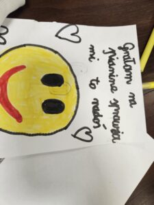 Rysunek dziecka z żółtą uśmiechnięta emotikonką.