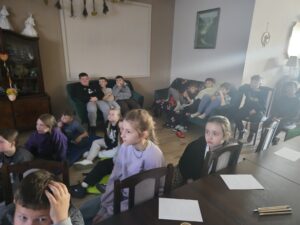 Grupa dzieci oglądająca projekcję na ekranie.