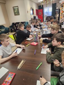 Dzieci rysujące na kartkach kredkami.