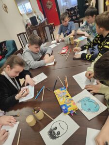 Dzieci rysujące na kartkach kredkami.