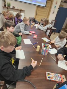 Dzieci rysujące na kartkach kredkami.