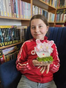 Dziewczynka trzymająca w rękach zajączka, wykonanego własnoręcznie z plastrów drzewa i ozdób.