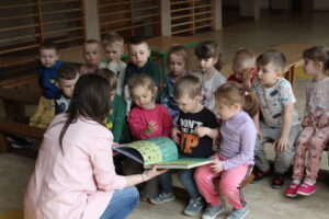 Dzieci i kobieta oglądające wielką książkę.