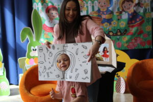 Kobieta z książką z dziurą, w której jest twarz dziecka.