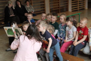 Dzieci i kobieta pokazująca książkę.