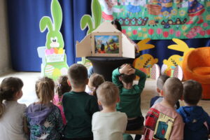 Dzieci słuchające czytanego teatrzyku Kamishibai.