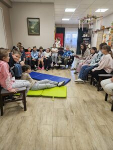 20260617_091634 Dzieci słuchające czytanej przez kobietę książki.