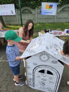 Dzieci i kobieta, kolorujące domek - kolorowankę przestrzenną.