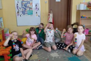 Grupka wesołych dzieci, siedzących na dywanie.