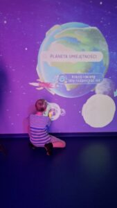 Chłopiec przy interaktywnej ścianie z planetami.