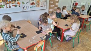 Dzieci w przedszkolu robią wydrapywanki przy stolikach.