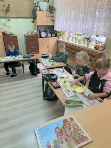 Grupa dzieci wykonuje słoneczniki z papieru.