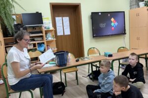 Kobieta czyta dzieciom książkę.